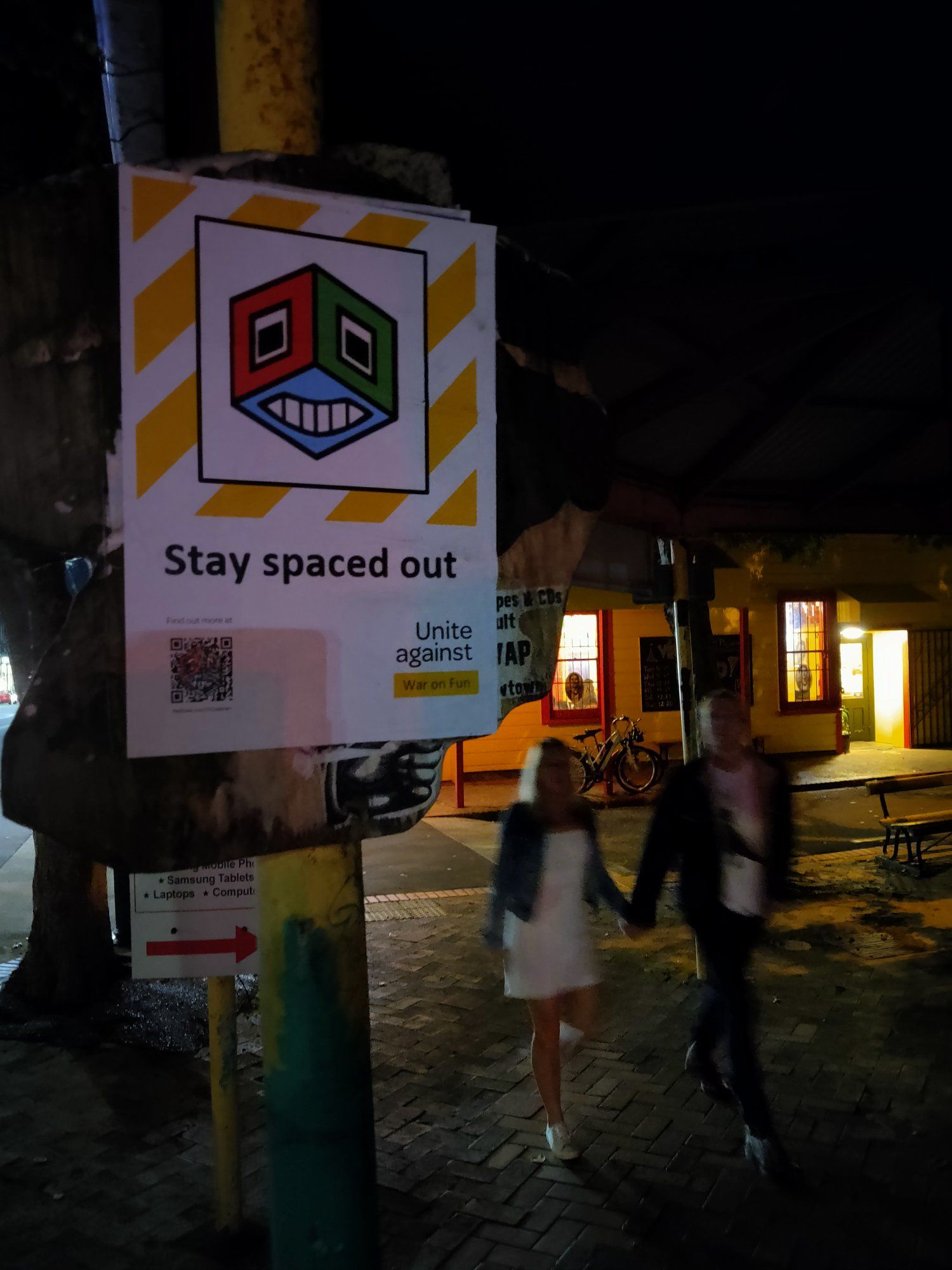 A Covid QR sign-in-style poster with the striped yellow and white border, but instead of a QR code is Cubeman&#39;s logo and the text &#39;Stay spaced out&#39;